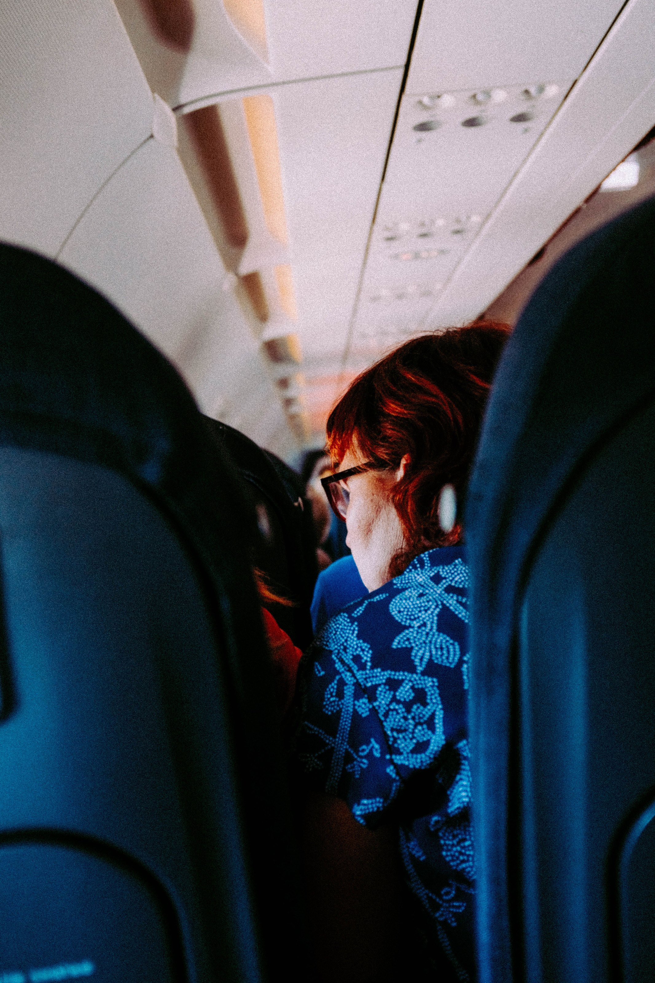 A woman seen between the seats of an aircraft cabin