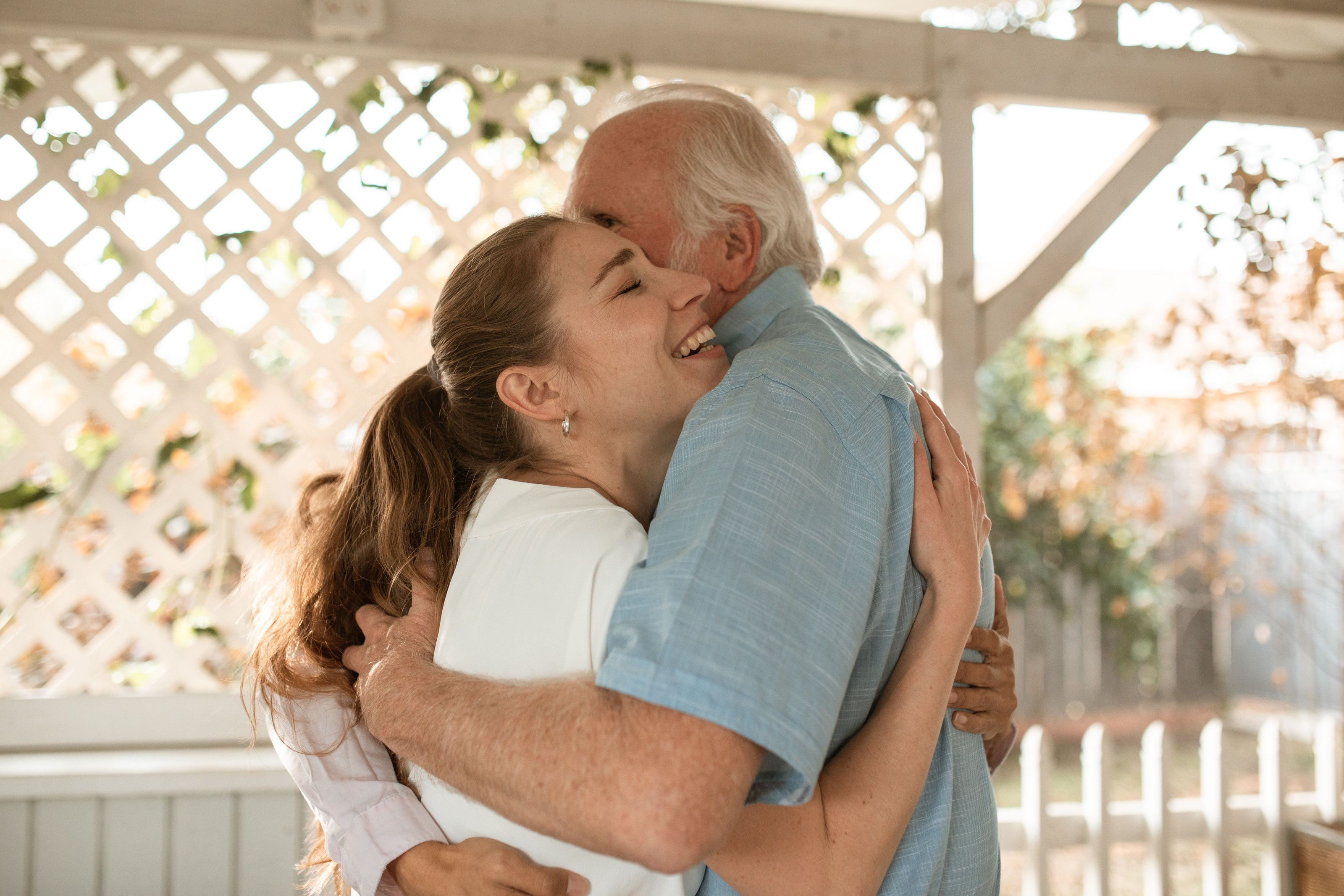 A young woman hugging an older man in a garden