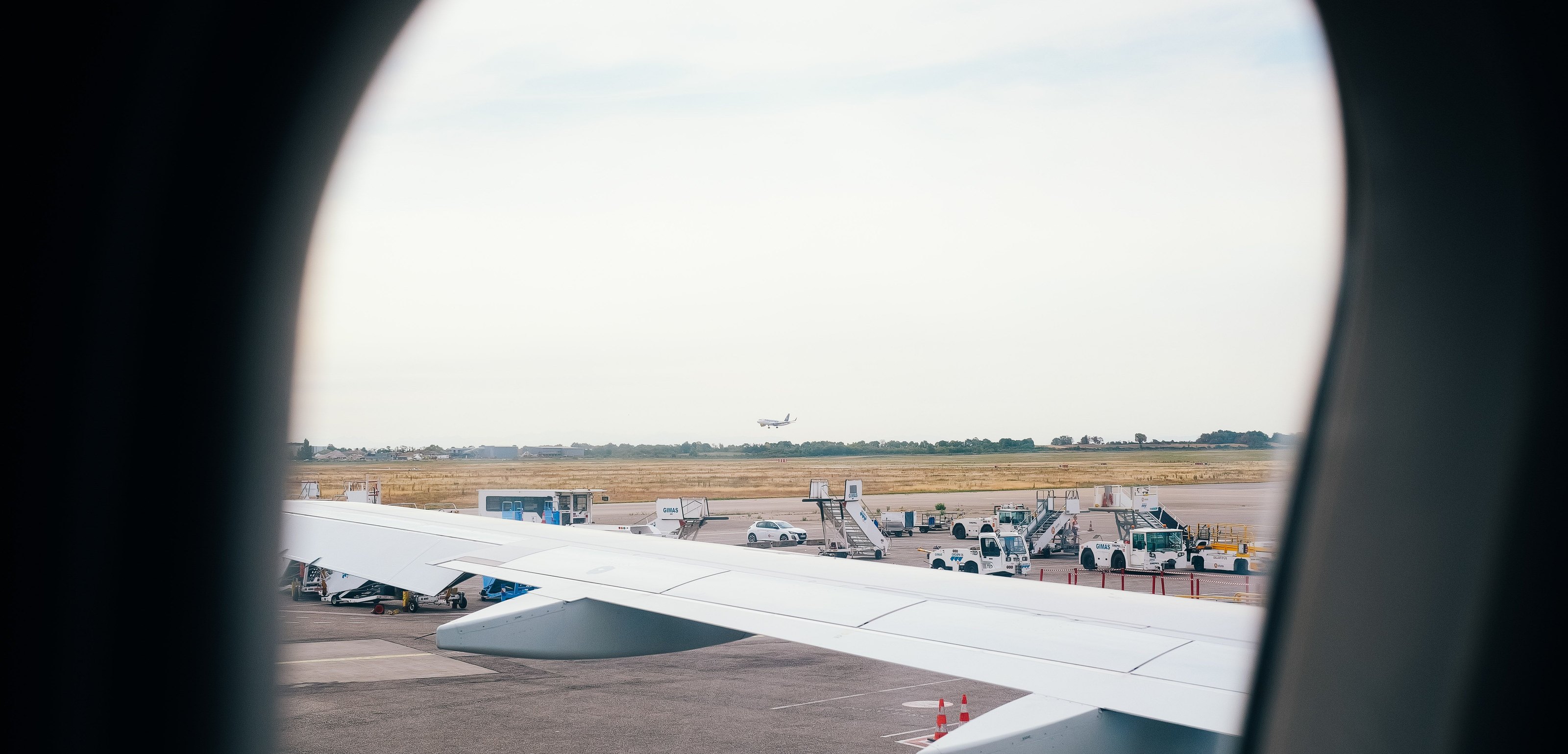 The wing of an aircraft seen through a cabin window, on the runway
